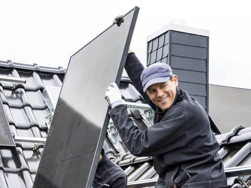 Monteur tilt een zonnepaneel op een schuin dak