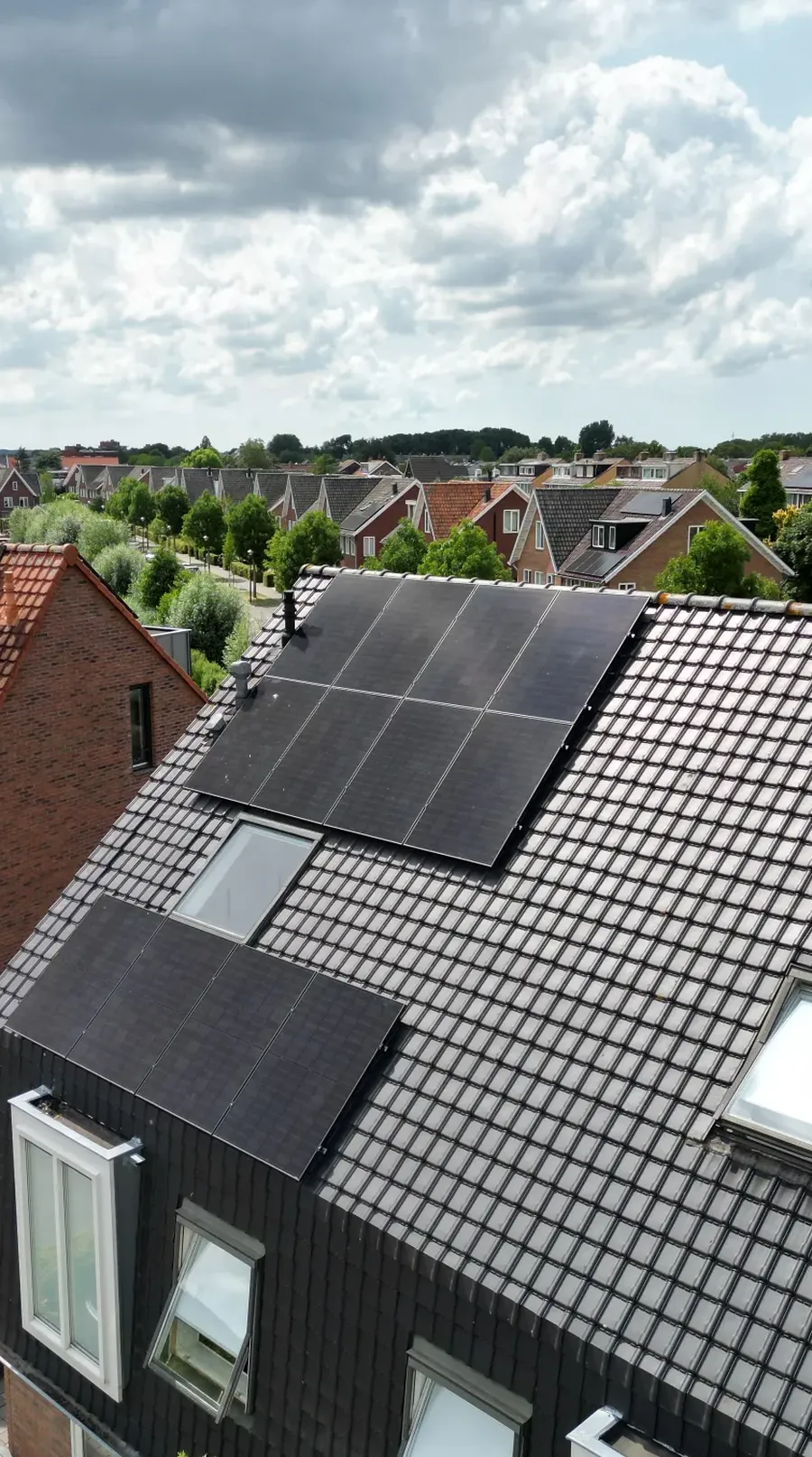 Zwart dak met strak gelegde zonnepanelen rond de dakramen